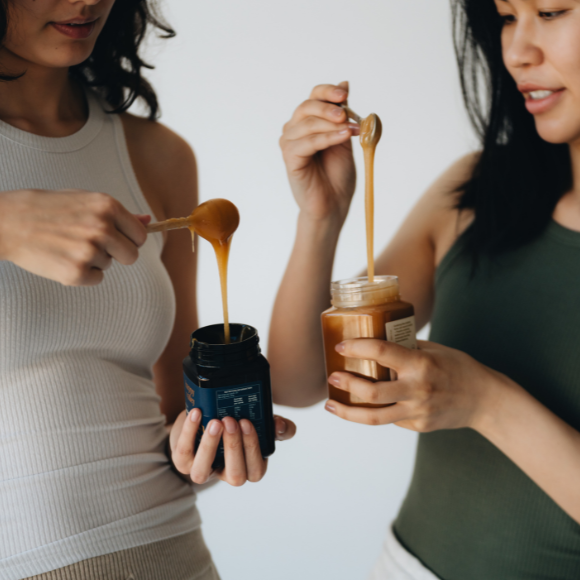 Women stirring honey in a jar