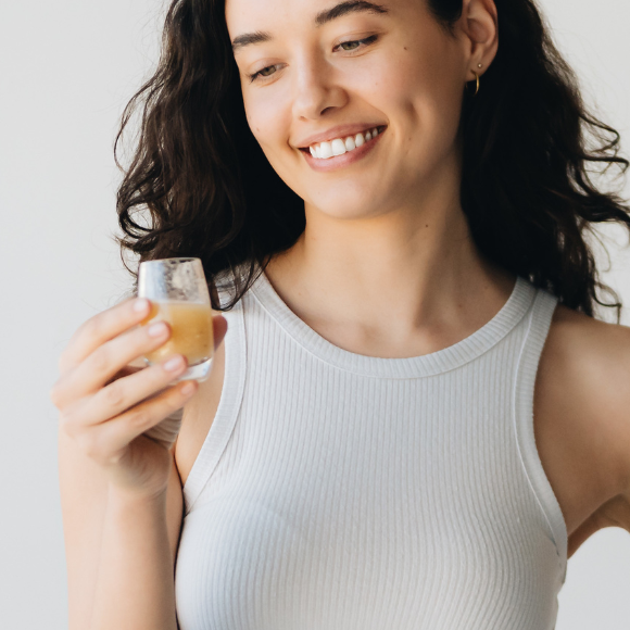 Joyful woman holding a cup in one hand