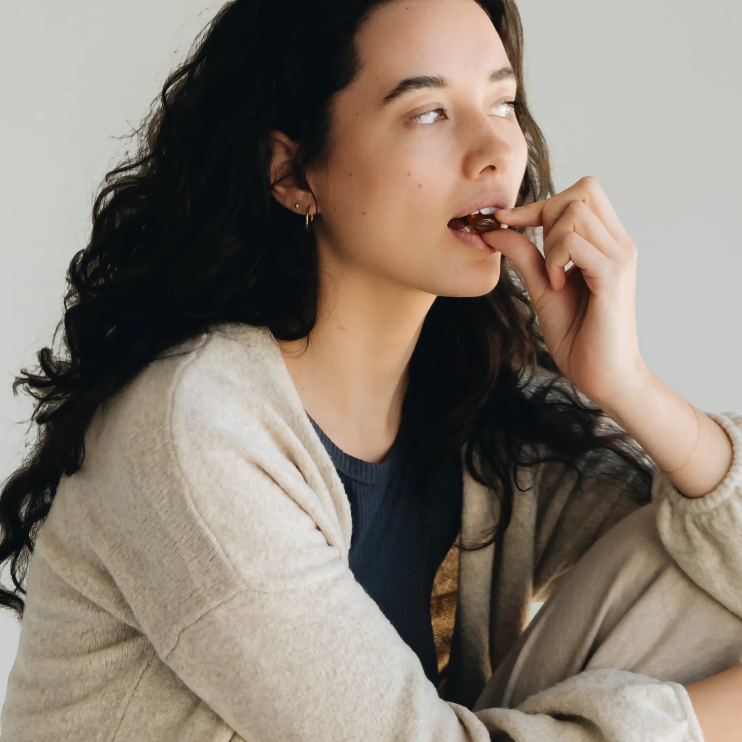 Happy Valley Honey Manuka Honey & Propolis lozenge being placed in mouth by a woman with dark curly hair.